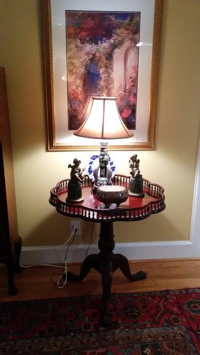 Nicely carved wooden tilt-top gallery table, with a pair of vintage French brass angels and a silver plated Swiss music box. 