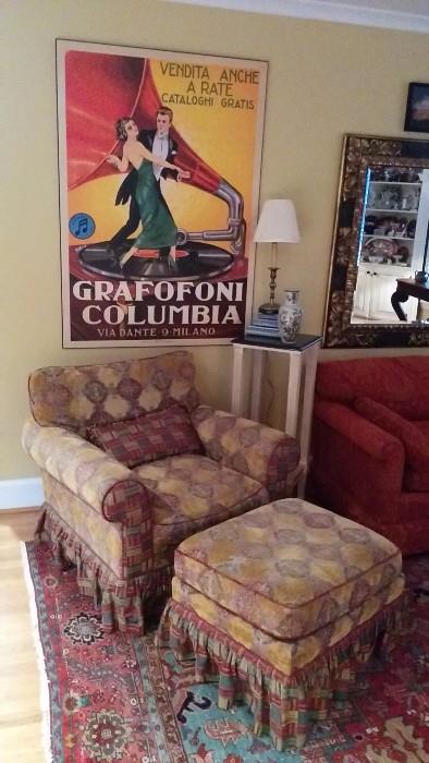 Large European Grafofoni Columbia poster, lording over the most comfy overstuffed chair and matching ottoman, resting on my favorite Persian Serapi. Flanked by black marble topped side table. with heavy brass table lamp. 