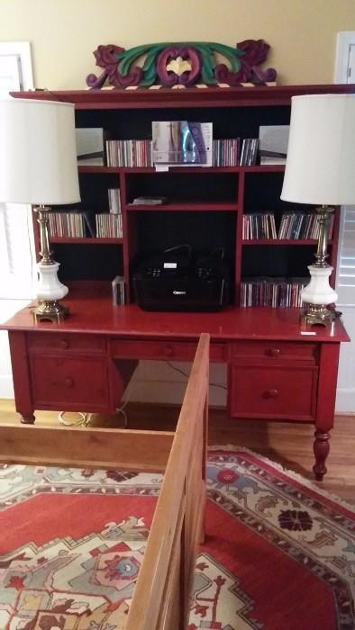 Red stained desk/bookcase (originally retailed for $2,500.00), loaded with CD's and flanked with a pair of vintage Stiffel lamps, w/white porcelain bases. 