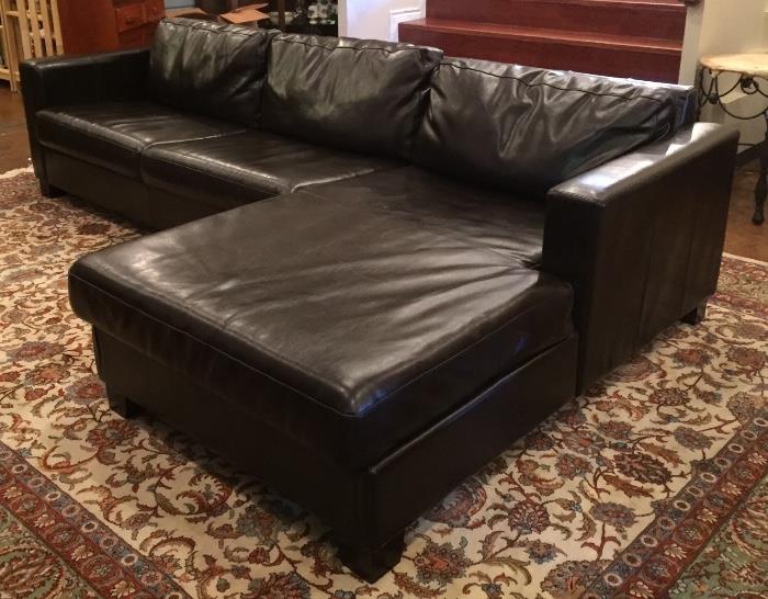 Brown vinyl contemporary sofa with chaise and room size rug.