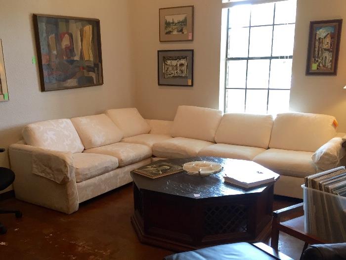 White sectional sofa, art, slate topped octagonal coffee table. 