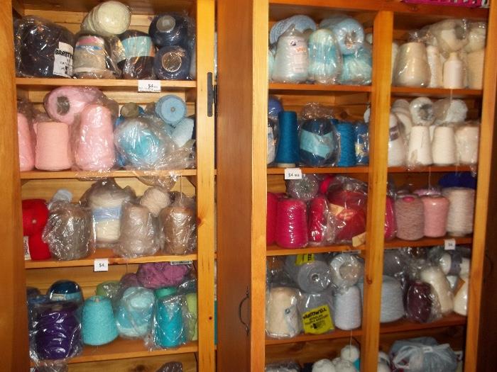 Large roomful, shelf after shelf filled with spools of knitting machine yarn as well as hand knitting yarn