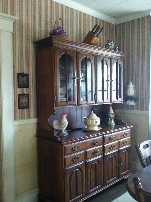 China cabinet with two sets of glass doors, two sets of wood, and two shallow drawers. Contains a variety of glassware and other small items.