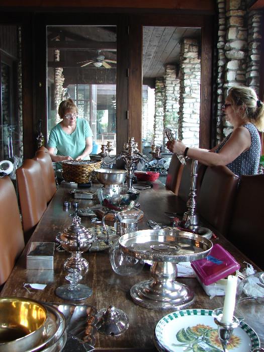Pam and Rita pricing some of the unbelievable number of items of silver of all types. Large serving trays, 12 ice buckets, 6 water pitchers, 12 champagne coolers, many, many serving pieces of all types. Enough to stock a boutique