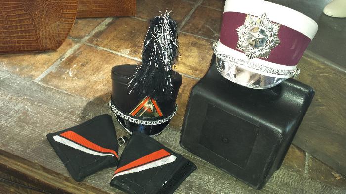 There are 100 black and silver band hats (shakos) with plume, and carrying case. As many maroon and white shakos (no plumes)
