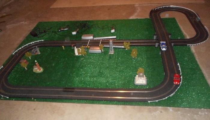 Great Looking Electric Race Track                                      Includes: Hand Triggers,  cars, small trees and various scenes everything in the
photos are included. Digital Transformer and 3 trigger gun controllers
You will have to disassemble it.
You will need an area that is at least 9 Ft. x 8 Ft. for this race track.