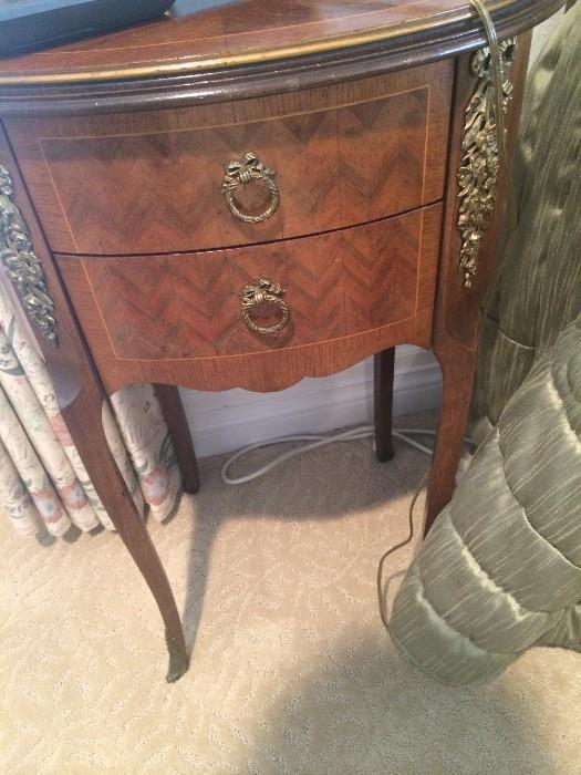 Ornate hardware adorns the oval-shaped side tables.