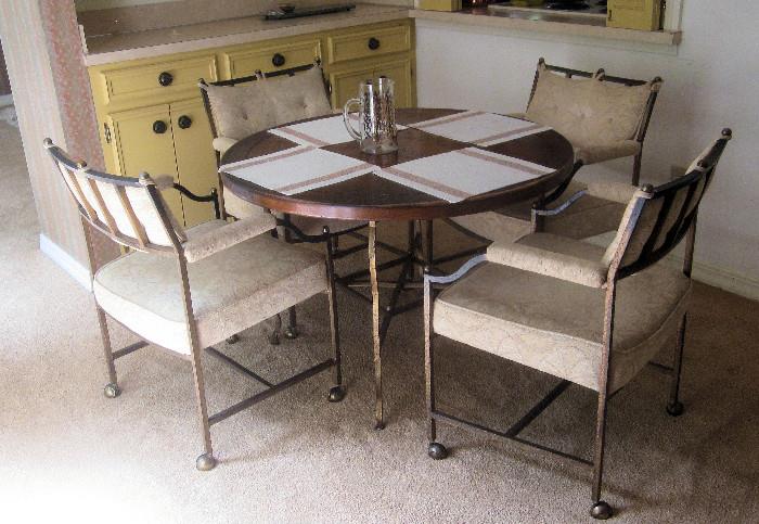 Round iron and wood breakfast table with four upholstered chairs on casters. Wooden table top has herringbone pattern.