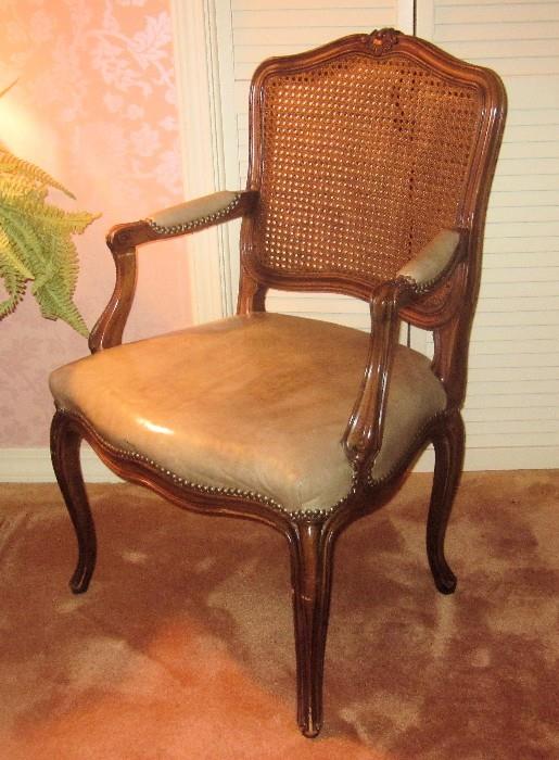 Great-looking, open arm, carved French chair with cane back and leather upholstered seat and arms. This is a fine piece of furniture manufactured by John Widdicomb. The bottom of the chair has a brass plaque attached, which reads: John Widdicomb Co. / Makers of Fine Furniture / Grand Rapids.
