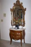 Lovely marble-top commode chest with mirror and table decor.