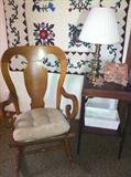 Antique oak rocking chair, vintage table, quilted wall hanging.