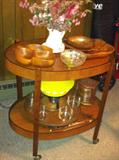 Vintage serving cart shown with wooden bowls, fondue set and more.