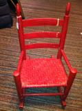 Antique child's rocking chair, woven seat, painted red.