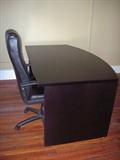 Two alike--nice contemporary black office desks and at least one executive chair.