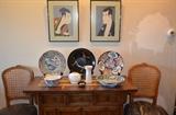 Japanese prints, Danish Modern ceramics, center, Japanese/Imari platter, Road Runner Bowl center, on Asian style high quality rolling server. Antique Carved Italian chairs, seats need reupholstering.