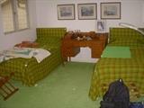 1970's era room with upholstered twin headboards and matching bedspreads.  Between beds is an "Early American" style desk