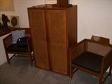 Caned door cabinet flanked by caned panel chairs