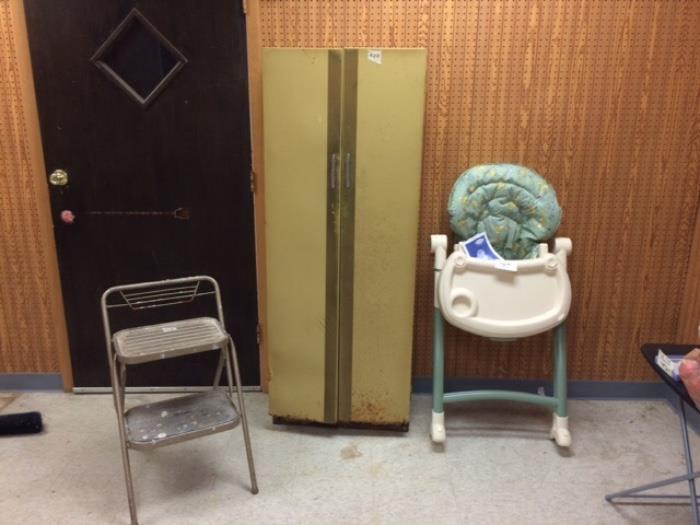 Two-step folding stool, two-door harvest gold shelved cabinet, and high chair.