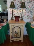 Dining Room:  A rooster theme cabinet has one interior shelf.  Two green metal toile lamps are on top of the cabinet.