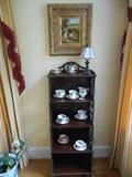 Living Room: The vintage curio/bookcase is 52" tall and has five shelves.  Also shown are a bunny rabbit painting, a collection of cups and saucers (including one 5-piece dessert set); and a small glass shade lamp.