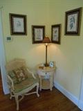 Living Room:  A Country French cane back chair with toile seat cushion and pillow is near a coordinating round/one drawer table and a 36" tall twisted candlestick lamp.  On the wall are four vintage floral prints (all priced separately) in black frames.
