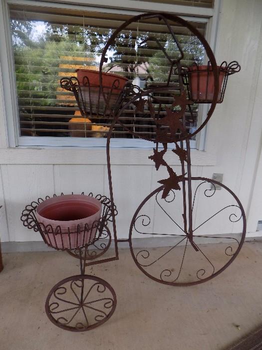 wrought iron tricycle plant stand shown with hanging star yard art