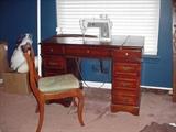 Sewing machine in desk with one of two side chairs