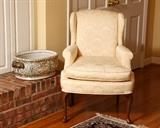 Small pale yellow wing chair and porcelain tub.