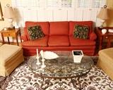 Den grouping with soft red sofa and glass topped coffee table.