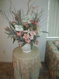 large silk floral arrangement on table with glass top and skirts
