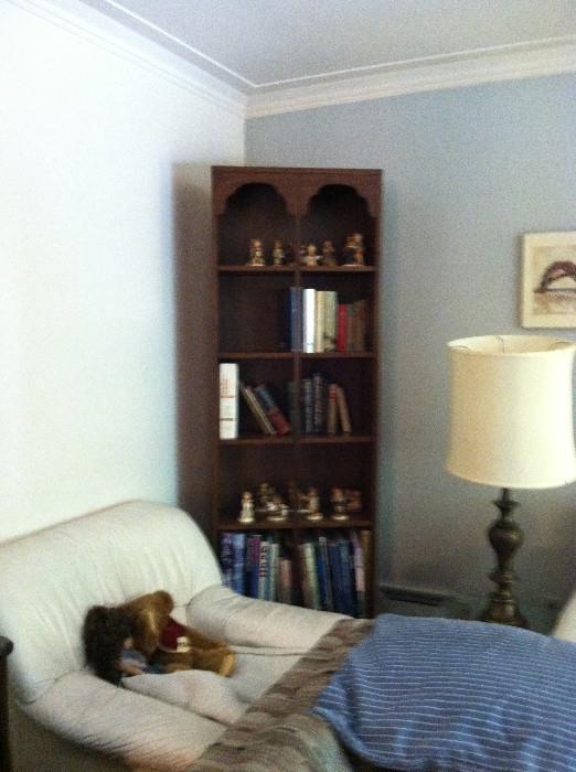 Bookshelf/display case, white leather chair, lamp.