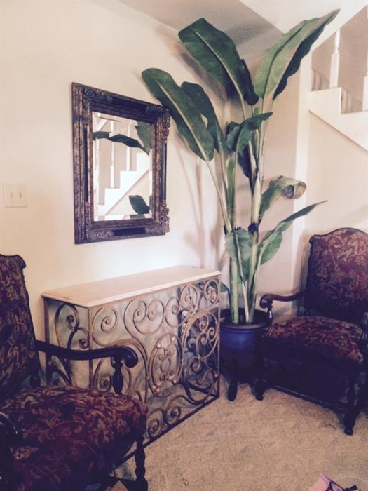 very nice pair of vintage chairs, newly upholstered; gold washed iron credenza with stone surface, banana tree, nice planter on an iron tripod, and beveled mirror.