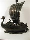 70.	Chinese Bronze Ship Sculpture,, circa 1960.      Pre-sale est. $850
Unknown, and markings are illegible, bronze sculpture of Chinese sailing ship, with Chinese symbols and designs.  Measures 13-5/8” high and 12-1/2” long. 

