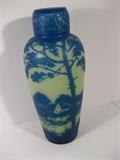 18.	French “Touchard” Glass Vase, circa 1915.     Appraisal Est. $1550
Cameo blown glass, and carved vase, with tapered body and narrowed neck. Chinese styled lake landscape in blue over a white background. Only the neck is carved, while the body has the enamel overlay. Signed “Touchard” on the side of the vase. 12” high.
