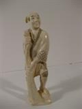49.	Japanese Carved Ivory Fisherman, circa 1940                         Pre-sale Est. $450
This carved ivory figure is a Japanese fisherman, barefoot with foot on rock, holding fishing net, draped at the base. Older faded chop mark on base is difficult to discern due to age. 6” tall
