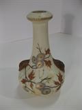 10.	German Porcelain Vase, circa 1890     Appraised Est. $575
Bottle formed vase with open, lozenge-form rim. Decorated with Chrysanthemum and ivy motif in polychrome enamels and two applique leaves on the shoulders. Rim has a serrated band. 6” high. German, New York and Rudolstadt Pottery, Thuringia
