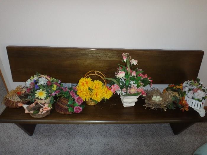 Solid wood bench with assorted flower arrangements. 