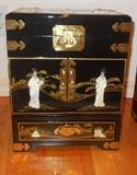 Beautiful black lacquer jewelry chest with 3-d design and brass fittings. Top lifts up and has a mirror. Two doors in middle open to access pull out drawers.