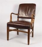 Item Description: A handsome Shearman Bros. Company arm chair boasting a leather upholstered back and seat with tack accents, having carved wooden arms and reeded legs with stretchers.
