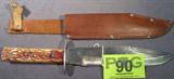 Tramontina Carbon Steel Blade Knife Leather Sheath
A large Tramontina carbon steel blade knife with what appears to be a bone handle. Includes a leather sheath, the strap that snaps over the knife handle is broken. Blade is 9.5" long. Knife is 15" long.