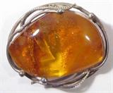Jewelry Sterling Silver & Amber Ladies Brooch
Lovely sterling silver ladies brooch featuring large amber stone, unique shape, accentuated by an intricate vine style design surrounding the stone, bar pin clasp at the back, measures 1.5" x 1.25" (est). Consigner affirms piece is sterling silver, while unsigned.
Total weight: 0.37 ozt