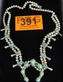 Jewelry Sterling Silver Squash Blossom Necklace
Fabulous large Southwestern style sterling silver squash blossom necklace featuring several turquoise nugget stones. Naja pendant is accented with 7 turquoise stones. The stones are bordered with a twisted rope style design. Unmarked, consignor states this item is sterling. Measures: 28" long, total weight: 3.69 ozt.