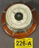 Airguide Marine Barometer
A marine / nautical barometer made by Airguide. Gauge has measurements in millibars and in inches. Barometer is set in a chrome casing, in the shape of a ship's steering wheel, and mounted to a wooden base. Working condition is unknown. Measures 7.75" in diameter.