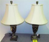 Lot of 2 Grecian Urn Style Table Lamps w/ Shades
A gorgeous pair of table or desk lamps with a Grecian urn style base and empire bell shaped cloth shades. Base is a combination of wood and metal with gold trim accents. Lamp shade is a neutral beige color. Measures 31" tall and the shade has a 17" diameter.