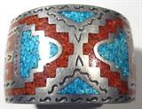 Jewelry Sterling Silver Coral & Turquoise Bracelet
Stately sterling silver cuff bracelet accented with inlaid polished red coral and turquoise stones in mosaic style design. Unmarked, consignor states this item is sterling. measures: 5.25" wide with 1" opening. Total weight: 2.20 ozt.