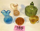 Mixed Lot Candy Dish / Vases / Flower Frog
A great mixed lot of decorative glassware items which include:
- An amber glass flower frog with 11 holes. Measures 3" in diameter. There are several small chips around the top openings.
- A pretty blue cracked glass design double top flower vase which appears to be hand blown. Measures 5" tall.
- A uniquely shaped amber dish with a wire handle. Possibly a toothpick holder. Measures 3" tall.
- A light pink cracked glass vase with a fluted top and curved handle. Appears to be hand blown glass. Measures approximately 5" tall.
- A green pressed glass candy dish. Octagon shaped dish with a tapered lid. Measures 5.5" tall with a 5" diameter.