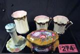 Mixed Lot Vanity Glassware R.S. Hat Pin Holder
A fantastic lot of glassware to brighten up your vanity or sink. Lot includes:
- A pretty porcelain hat pin holder featuring a floral pattern with gold gilt accents. The hallmark stamped on the bottom is for the R.S. Prussia / Germany porcelain factory. Measures approximately 5" tall with a 3.5" diameter.
- A three piece porcelain set; glass, cup, and mustache cup. This white glassware has beautiful gold gilt accents and a frosted pink shade around the inside rims. The glass measures 5" tall. The other cups are approximately 3.5" tall.
- A porcelain trinket box which appears to be hand painted with gold gild accents. Made in China. Measures 3.75" tall.