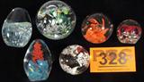Lot of 6 Art Glass Paperweights
This lot contains 6 uniquely designed paperweights:
- A beautiful orange flower with butterflies hovering above it. Measures 2.75" tall.
- A lovely red and multi color floral pattern. Measures 2" tall.
- A white and brown floral design. Measures 2.25" tall.
- A gorgeous green and multi color floral design with strategically placed air pockets. Measures 2.75" tall. This paperweight has an undetermined signature on the bottom.
- An oval shaped paperweight with a flowing blue pattern. Measures 3" tall.
- An oval shaped paperweight with multi color swirls and an orange spiral shaped design. Measures 3.25" tall.