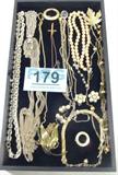 Jewelry Mixed Lot Costume Gold Chains & More
A beautiful lot of vintage gold color chains and more. Lot includes:
- A gold color chain with a small heart pendant featuring a pearl in the center of the heart.
- A gold color round pin, signed "Trifari"
- A solid copper cross shaped pendant on a chain.
- A long triple chain necklace with a metal tassel style pendant.
- An old double strand pearl like necklace.
- A gold color brooch featuring a triple leaf design.
- A mustard seed pendant on a silver color chain.
- Many more pretty items.