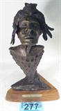 Art Bronze Statue "Teller of Tales" Rufus Coomer
A very unique bronze sculpture featuring what appears to be a Native American Indian with a bear skin and feather head dress. The head sits atop an arrow head shape piece. The bronze is affixed to a wooden base which is labeled "Teller of Tales" by Rufus Coomer. Bronze is also signed and titled. Measures 14" tall.